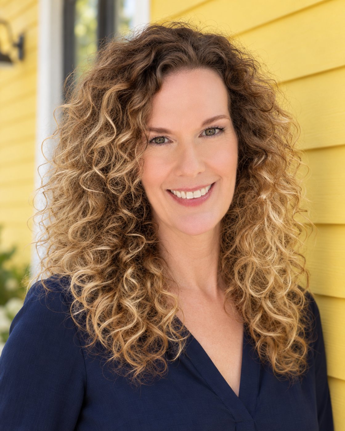 Cindy smiling in front of a bright yellow house